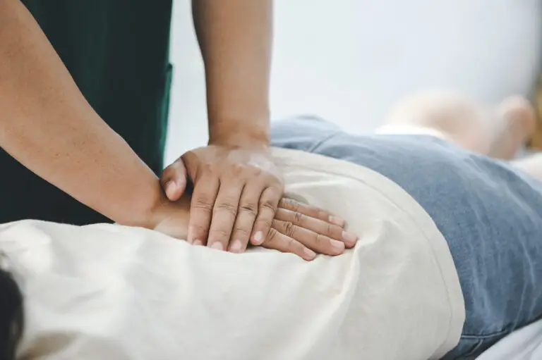 A physiotherapist applying manual therapy to treat a patient's lower back.