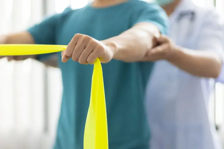 A physiotherapist assisting a patient with a shoulder exercise using a resistance band.