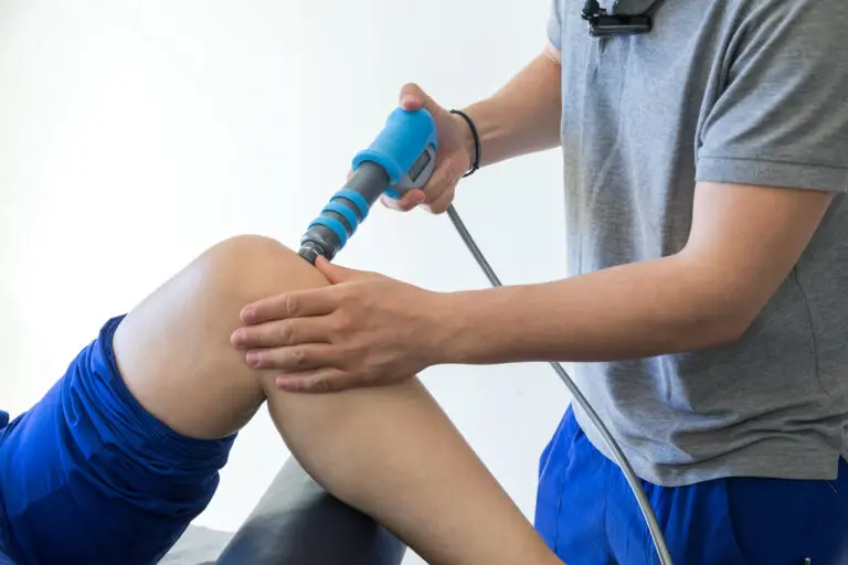 A therapist administering shock wave therapy to a patient's knee.